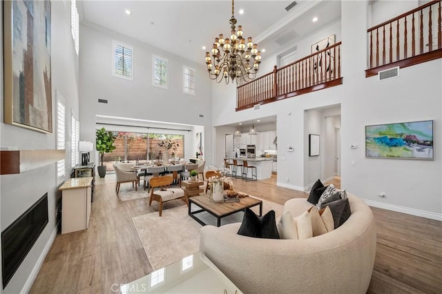 53 Interlude, Irvine, CA 92620 - living room with ornamental molding, light wood-style floors, a chandelier, a towering ceiling, and recessed lighting