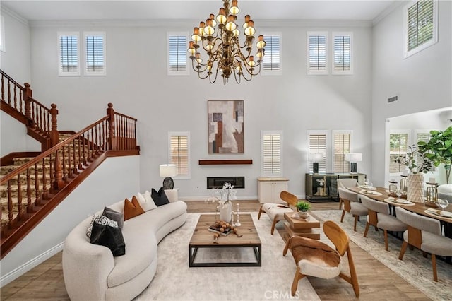 53 Interlude, Irvine, CA 92620 - living room featuring crown molding, wood finished floors, a glass covered fireplace, a towering ceiling, and stairs