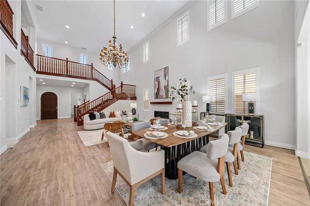 53 Interlude, Irvine, CA 92620 - dining area featuring a towering ceiling, stairs, light wood-type flooring, a chandelier, and a glass covered fireplace
