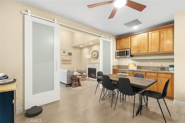 24912 Hearth Ct, Valencia, CA 91354 - dining area with a barn door, a ceiling fan, light wood-style floors, a warm lit fireplace, and recessed lighting