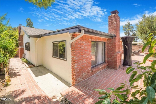429 Walter Ave, Newbury Park, CA 91320 - view of side of home featuring a patio area, a chimney, stucco siding, and brick siding