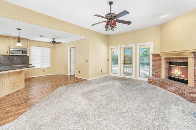 9425 Oak Hills Ave, Bakersfield, CA 93312 - unfurnished living room featuring ceiling fan, a brick fireplace, light wood-style flooring, and light colored carpet