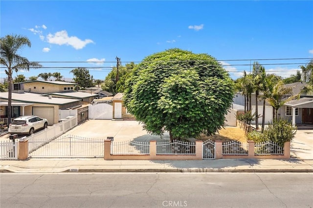 13162 Oaks Ave, Chino, CA 91710 - view of property hidden behind natural elements featuring a gate, a fenced front yard, concrete driveway, and a residential view