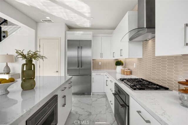 100 Soaring Eagle, Irvine, CA 92618 - kitchen with built in appliances, wall chimney exhaust hood, white cabinetry, light stone countertops, and decorative backsplash
