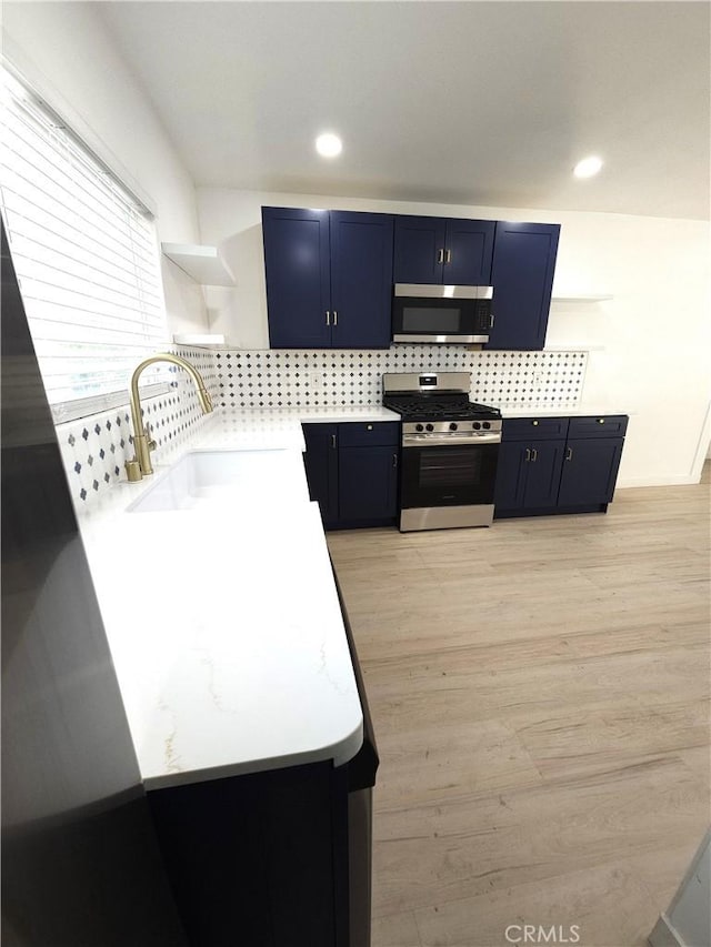 215 N Olive St, Anaheim, CA 92805 - kitchen featuring stainless steel appliances, open shelves, light countertops, blue cabinets, and backsplash
