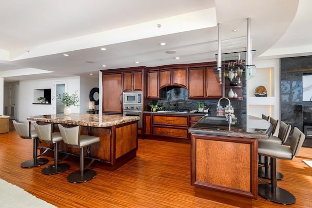 1325 Pacific Hwy Unit 3403, San Diego, CA 92101 - kitchen with appliances with stainless steel finishes, a breakfast bar area, wood finished floors, a kitchen island, and recessed lighting