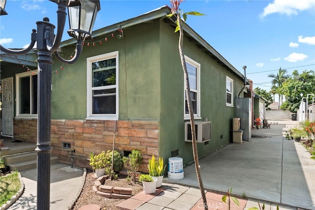 14057 Ohio St, Baldwin Park, CA 91706 - view of side of home featuring stucco siding, a patio area, stone siding, and cooling unit
