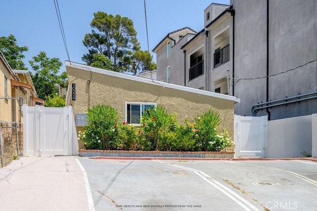 10224 Fernglen Ave, Tujunga, CA 91042 - view of home's exterior featuring a gate, uncovered parking, and stucco siding
