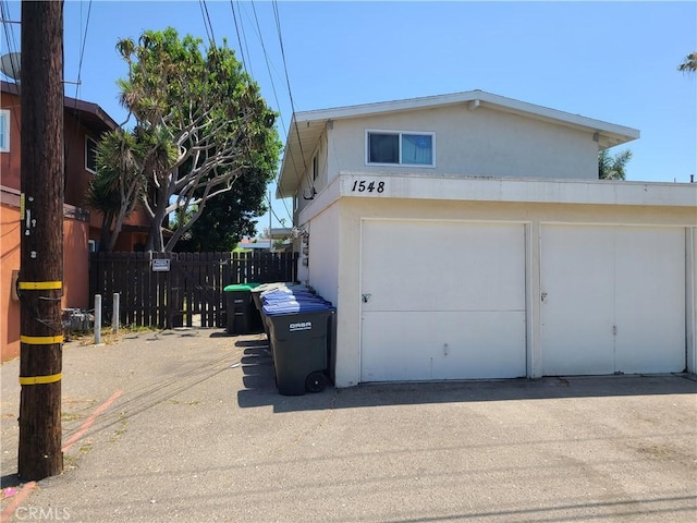 1548 N Elm Ave, Costa Mesa, CA 92626 - view of side of home featuring a garage, asphalt driveway, and stucco siding