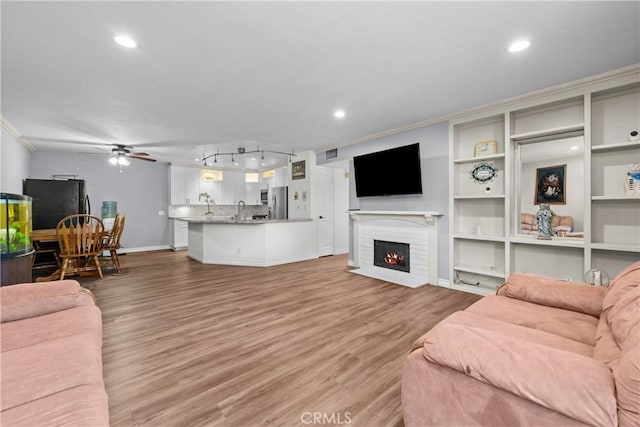 3611 S Bear St Unit D, Santa Ana, CA 92704 - living room with a ceiling fan, light wood-style flooring, crown molding, recessed lighting, and a brick fireplace
