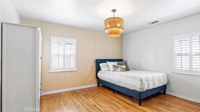 3209 Bennett Dr, Los Angeles, CA 90068 - bedroom with wood-type flooring, multiple windows, wallpapered walls, and a chandelier