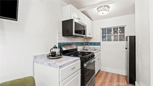 3209 Bennett Dr, Los Angeles, CA 90068 - kitchen featuring appliances with stainless steel finishes, light countertops, decorative backsplash, white cabinetry, and light wood-type flooring