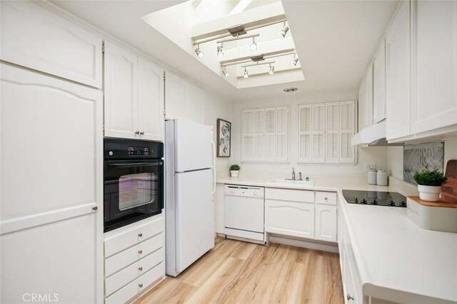 933 Avenida Majorca Unit P, Laguna Woods, CA 92637 - kitchen featuring black appliances, under cabinet range hood, white cabinetry, light wood-style floors, and light countertops