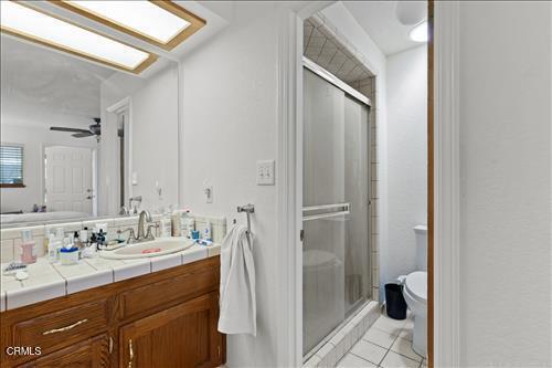 22820 Mariposa Rd, Tehachapi, CA 93561 - full bath with vanity, a shower stall, tile patterned floors, and a ceiling fan