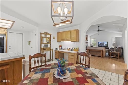 22820 Mariposa Rd, Tehachapi, CA 93561 - dining space with arched walkways, a ceiling fan, lofted ceiling, a chandelier, and light tile patterned floors