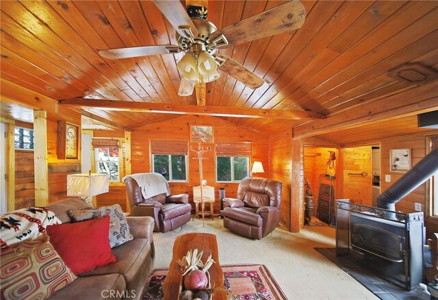 22052 Elliot Rd, Cedarpines Park, CA 92322 - living area with a wood stove, plenty of natural light, wooden walls, ceiling fan, and carpet flooring