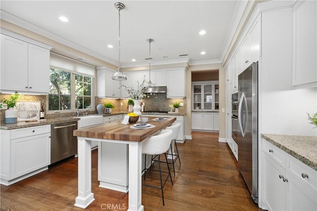 32 Tesoro, Irvine, CA 92618 - kitchen featuring appliances with stainless steel finishes, butcher block countertops, white cabinetry, dark wood-type flooring, and crown molding