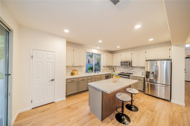 2455 Mcmackin Dr, Corona, CA 92881 - kitchen featuring appliances with stainless steel finishes, light wood-style flooring, decorative backsplash, a center island, and recessed lighting