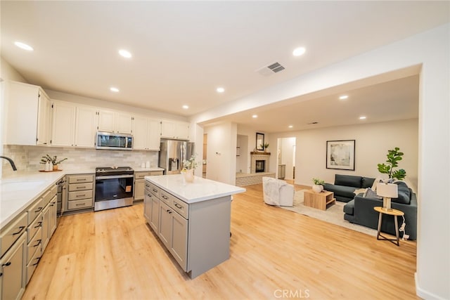 2455 Mcmackin Dr, Corona, CA 92881 - kitchen featuring stainless steel appliances, gray cabinetry, light wood-style floors, decorative backsplash, and recessed lighting