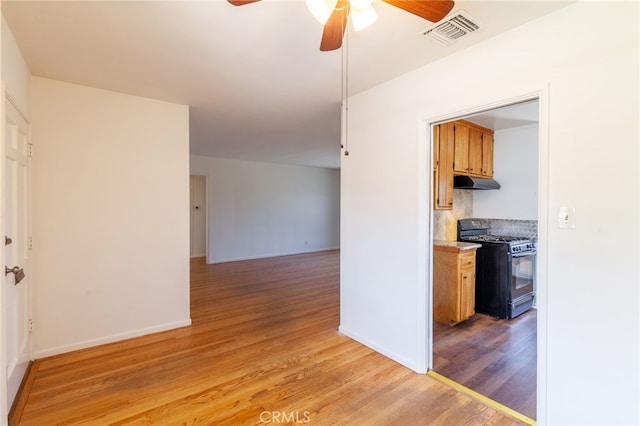 10935 Nassau Ave, Sunland, CA 91040 - kitchen with black range with gas cooktop, under cabinet range hood, a ceiling fan, light wood-style floors, and tasteful backsplash