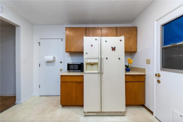 5064 N Berkeley Ave, San Bernardino, CA 92407 - kitchen with white fridge with ice dispenser, stainless steel microwave, brown cabinetry, and light countertops