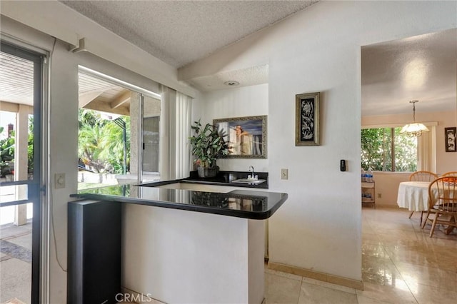872 Deborah St, Upland, CA 91784 - kitchen with a textured ceiling, light tile patterned flooring, dark countertops, lofted ceiling, and a chandelier