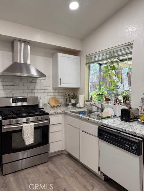 12446 Mount Baldy Dr, Victorville, CA 92392 - kitchen with stainless steel gas range, wall chimney range hood, white dishwasher, tasteful backsplash, and light wood-style flooring