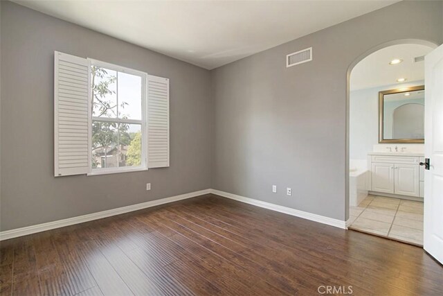 760 S Olive St, Anaheim, CA 92805 - unfurnished bedroom featuring hardwood / wood-style floors, arched walkways, ensuite bathroom, and recessed lighting