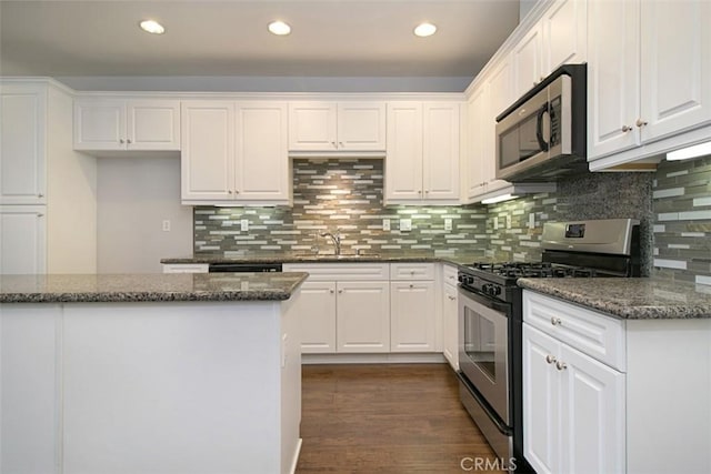760 S Olive St, Anaheim, CA 92805 - kitchen featuring appliances with stainless steel finishes, white cabinets, decorative backsplash, dark stone countertops, and recessed lighting