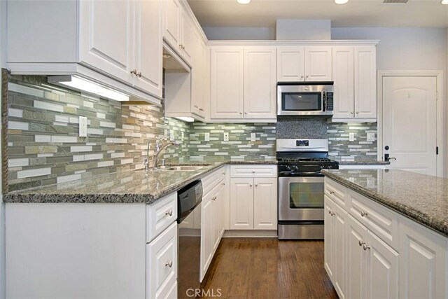 760 S Olive St, Anaheim, CA 92805 - kitchen with stainless steel appliances, white cabinetry, dark wood-style floors, dark stone countertops, and tasteful backsplash