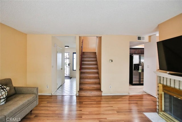8458 Evergreen, Garden Grove, CA 92841 - living area with light wood-type flooring, a textured ceiling, stairs, and a fireplace with flush hearth