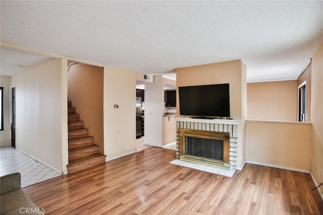 8458 Evergreen, Garden Grove, CA 92841 - unfurnished living room featuring wood finished floors, stairs, a textured ceiling, and a fireplace