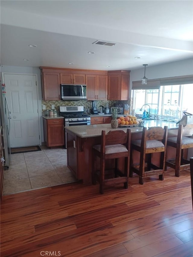 9849 Canada Way, Riverside, CA 92503 - kitchen featuring stainless steel appliances, decorative backsplash, light wood-style floors, a breakfast bar, and brown cabinets