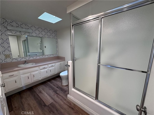 1271 Kenwood Unit 163D, Seal Beach, CA 90740 - bathroom featuring a skylight, an enclosed shower, wood finished floors, vanity, and wallpapered walls