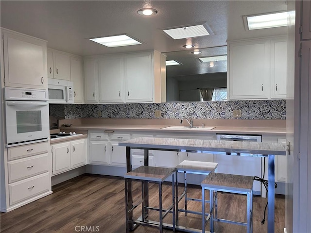 1271 Kenwood Unit 163D, Seal Beach, CA 90740 - kitchen with white appliances, white cabinetry, light countertops, and dark wood-style floors