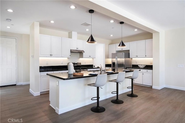 30316 Slate St, Murrieta, CA 92563 - kitchen with appliances with stainless steel finishes, dark countertops, white cabinets, a kitchen breakfast bar, and dark wood-style flooring