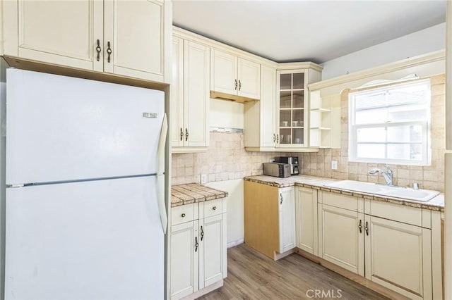 5516 Palm Ave, Whittier, CA 90601 - kitchen featuring freestanding refrigerator, backsplash, light wood-style floors, glass insert cabinets, and cream cabinets