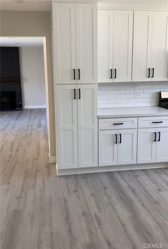 3195 Camarillo Ave, Oceanside, CA 92056 - kitchen with light wood-style floors, white cabinets, light countertops, tasteful backsplash, and open floor plan