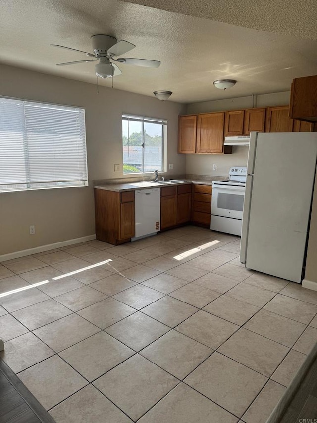 384 I St, Chula Vista, CA 91910 - kitchen featuring white appliances, under cabinet range hood, a textured ceiling, light tile patterned flooring, and brown cabinets