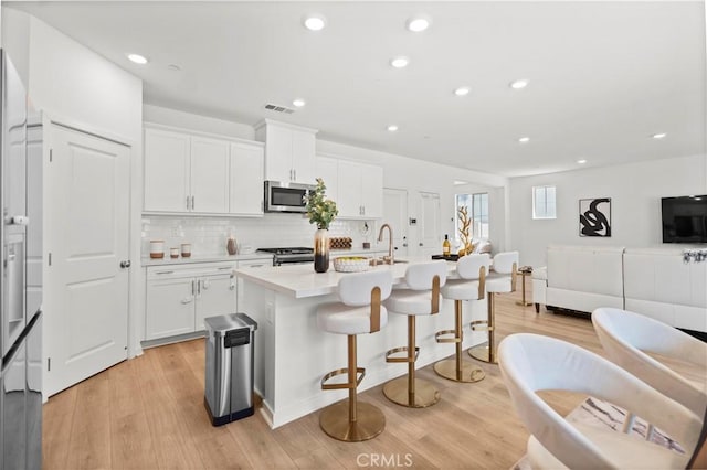 2239 Melogold Way, Corona, CA 92883 - kitchen featuring stainless steel appliances, light wood-style floors, backsplash, white cabinetry, and recessed lighting