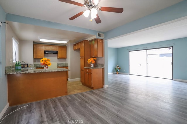 1818 W 145th St Unit 1, Gardena, CA 90249 - kitchen with brown cabinets, wood finished floors, stone counters, a peninsula, and ceiling fan