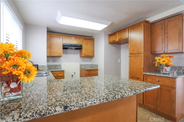 1818 W 145th St Unit 1, Gardena, CA 90249 - kitchen featuring under cabinet range hood, brown cabinetry, light stone counters, and a peninsula