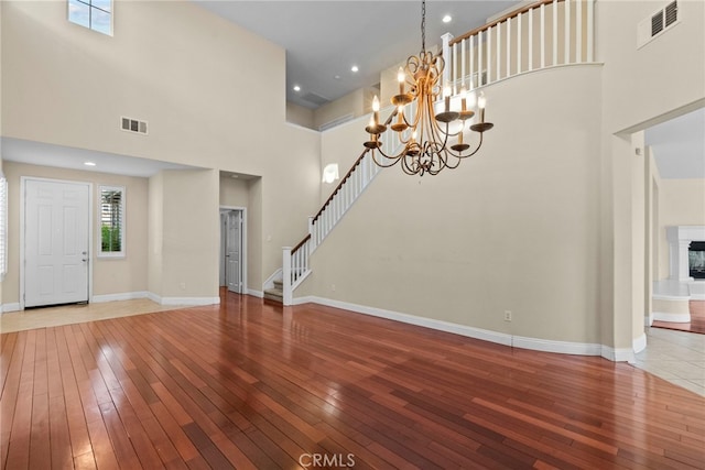 29243 Discovery Ridge Dr, Saugus, CA 91390 - unfurnished living room featuring a high ceiling, hardwood / wood-style floors, a chandelier, stairway, and a fireplace