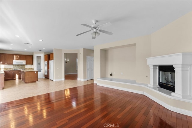 29243 Discovery Ridge Dr, Saugus, CA 91390 - unfurnished living room with light wood-style flooring, a ceiling fan, recessed lighting, a glass covered fireplace, and a chandelier