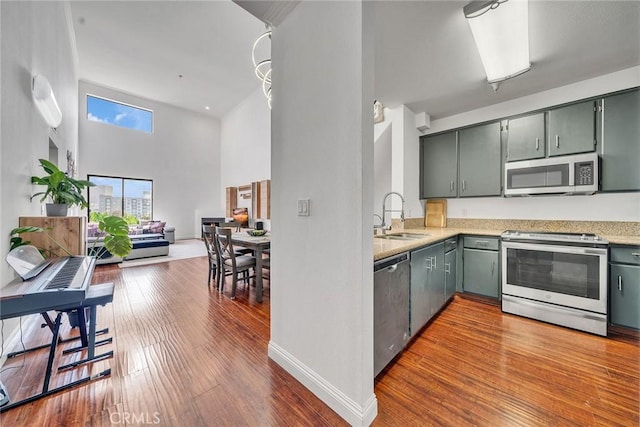 625 S Berendo St Unit 604, Los Angeles, CA 90005 - kitchen featuring stainless steel appliances, wood finished floors, a towering ceiling, light stone counters, and gray cabinets