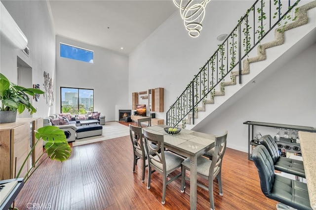 625 S Berendo St Unit 604, Los Angeles, CA 90005 - dining room featuring a high ceiling, stairs, a lit fireplace, and wood finished floors