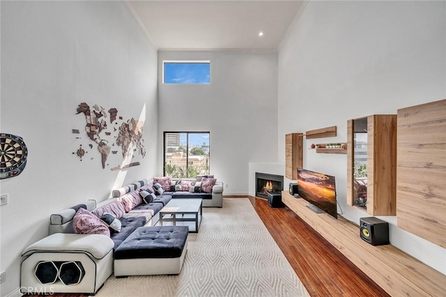 625 S Berendo St Unit 604, Los Angeles, CA 90005 - living area featuring ornamental molding, a high ceiling, healthy amount of natural light, wood finished floors, and a warm lit fireplace