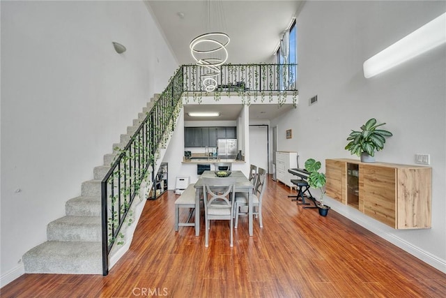 625 S Berendo St Unit 604, Los Angeles, CA 90005 - dining space with a high ceiling, stairway, wood finished floors, and a chandelier