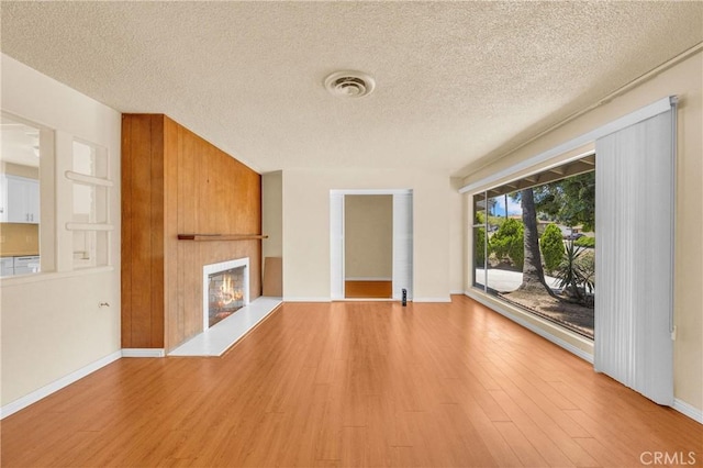 20468 College Blvd, Riverside, CA 92507 - unfurnished living room featuring a textured ceiling, a lit fireplace, and light wood-type flooring