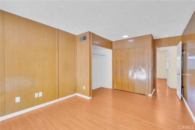 20468 College Blvd, Riverside, CA 92507 - unfurnished bedroom with wood finished floors, a textured ceiling, wooden walls, and a closet